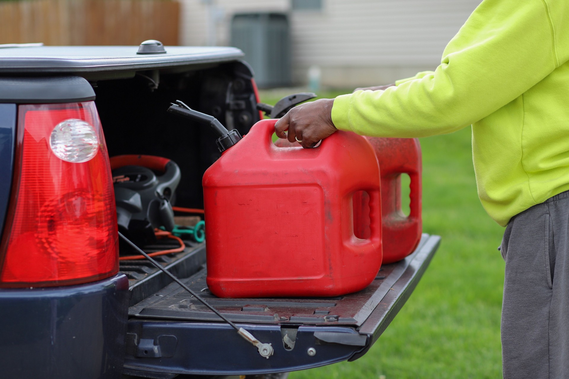 An African-American man holding two red plastic gas tank in a truck